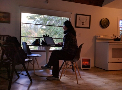Image of author seated at kitchen table in woodland cabin looking cozy.
